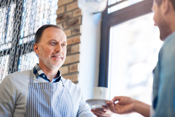Positive senior man holding cup of coffee