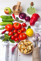 ingredients of gazpacho soup on white wooden table - tomatoes, cucumbers, garlic, basil