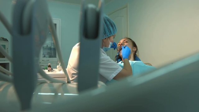 The dentist treats teeth of a young girl. 2 Shots