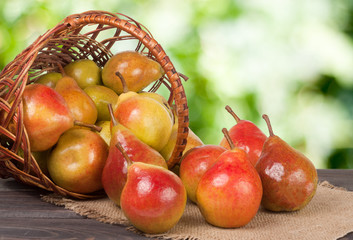 pears in a wicker basket on wooden table with blurred background