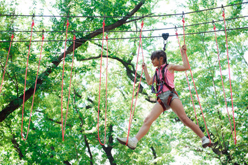 Naklejka na ściany i meble adventure climbing high wire park - hiking in the rope park girl