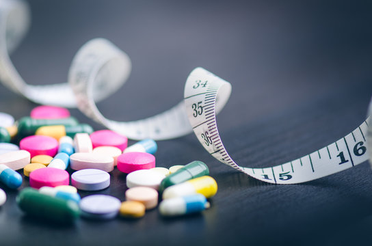 Pharmacy background on a black table with measuring tape. Tablets on a black background. Pills. Medicine and healthy. Close up of capsules. Differend kind of pills 