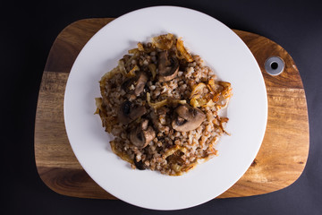 White plate with a buckwheat on wooden cutting board, dark backg