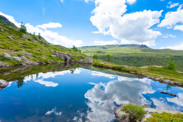 Naklejka na ściany i meble Italian mountain panorama, clouds reflected on alpine lake