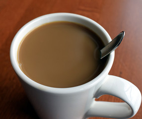 White coffee mug filled with coffee with cream.