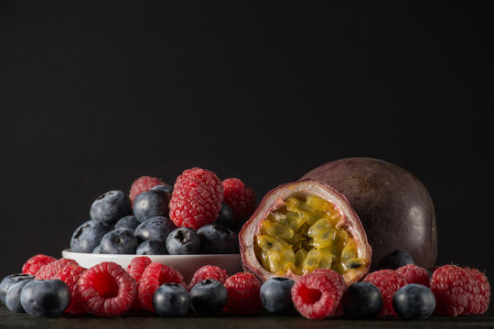 Raspberry and blueberry with a passionfruit, on dark background,