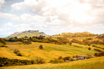 Fototapeta premium Beautiful tuscan landscape view on the green meadow with farmlands near Montepulciano town in Italy