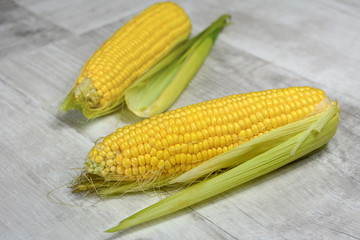 Fresh corn with green leaves on wooden table. 