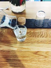 Pour water in a glass, wooden table in coffee shop