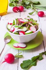 Vegetable salad with radish in a white bowl