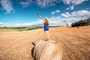 Naklejka na ściany i meble Young woman in blue dress enjoying nature on the hayfield in Tuscany in Italy