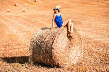 Naklejka na ściany i meble Young woman in blue dress enjoying nature on the hayfield in Tuscany in Italy