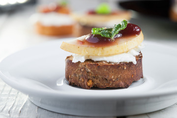 Bruschetta with goat cheese and pear on white plate