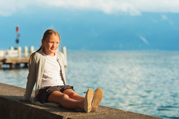 Fototapeta na wymiar Cute little girl resting by lake Geneva at sunset