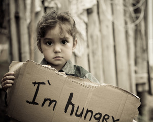 Little girl holding a sheet of cardboard. On the cardboard label 