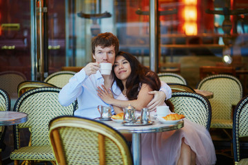 Couple drinking coffee and eating croissants in Parisian cafe