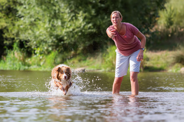 woman plays with her dog in the water