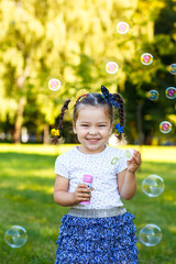 little girl blowing bubbles in the park