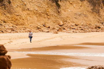 Fototapeta na wymiar Female traveler walking on the isolated beach Ursa on Atlantic coast near the Cape Roca, Sintra, Portugal