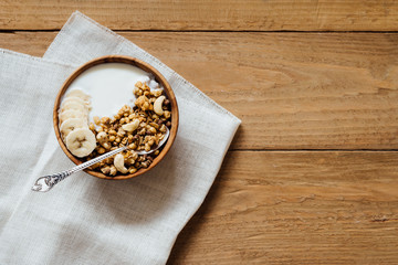 Homemade oatmeal granola with yogurt in wooden bowl