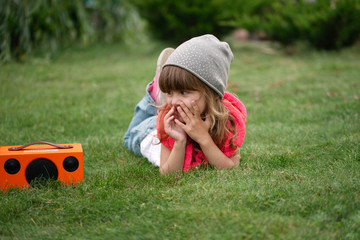 hipster girl listens music on wireless retro looking speaker