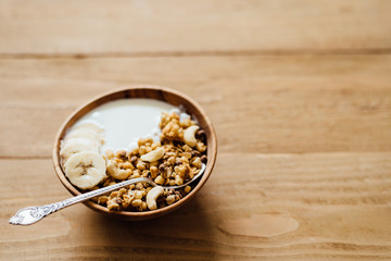 Homemade oatmeal granola with yogurt in wooden bowl