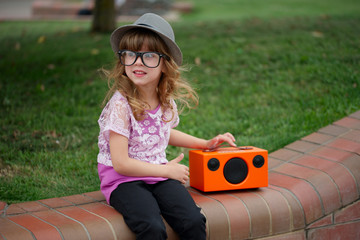 hipster girl listens music on wireless retro looking speaker