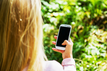 Young woman playing with mobile phone and resting in the park.