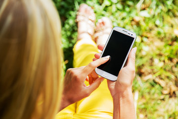 Young woman playing with mobile phone and resting in the park.