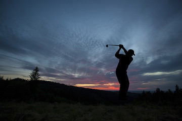 Golfer playing golf during sunset at competition event