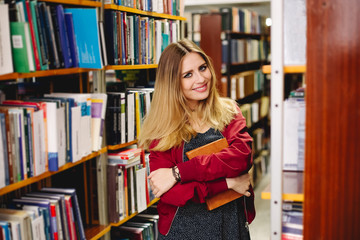 Smiling girl with a book in university library. Education concept