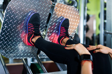 Close up shoes of a fit young woman doing leg press in the gym