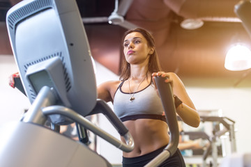 Fototapeta na wymiar Fit woman doing exercise on a elliptical trainer.