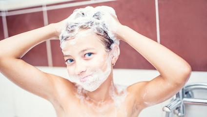 Cute young girl in shower washing hair and face with shampoo.