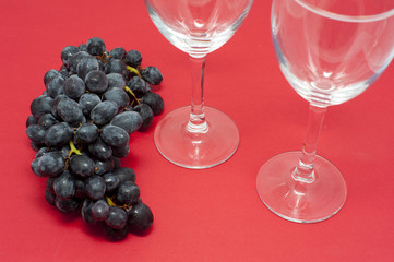 Grapes on Red Background with Empty Wine Glasses