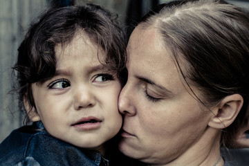 A woman holds a child, trying to calm him down. The child is three years.
