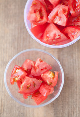 Fresh red tomato slice in glass bowl on wood table background