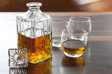 Bottle of whisky and three glasses on wooden table