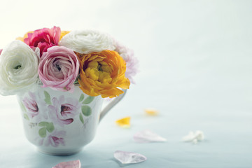 Colorful ranunculus flowers in a decorative cup