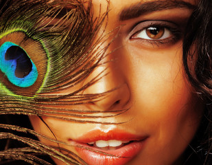 young sensitive brunette woman with peacock feather eyes close up on green smiling, lifestyle...