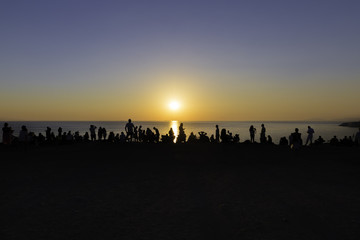 Fototapeta na wymiar People silhouette watching sunset on the edge of the cliff near Polente lighthouse at Bozcaada island