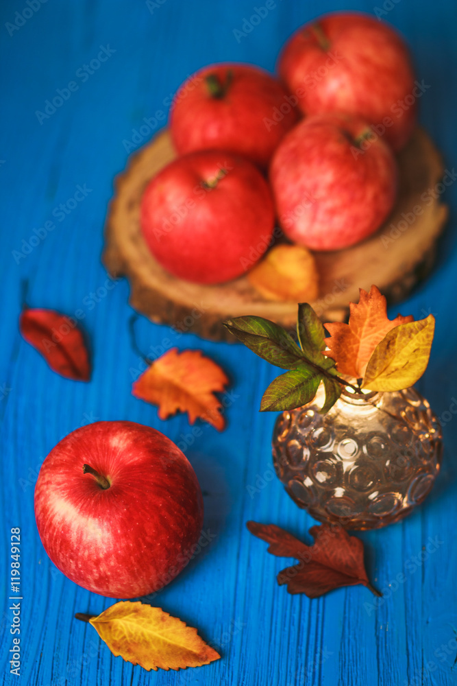 Wall mural Big red apple with autumn leaves on blue background - Wall murals