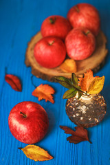Big red apple with autumn leaves on blue background