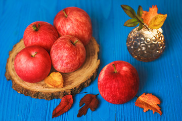Big red apple with autumn leaves on blue background