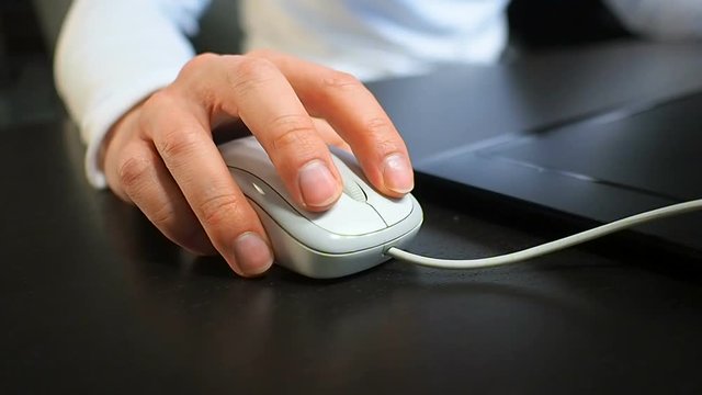 Mouse 8. Soft focus to hand of the man clicking left mouse button. Right hand from front front right view.