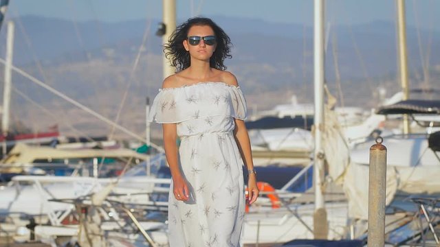 Beautiful sexy young woman wearing long white dress walking at a port