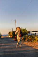 Obraz premium Stylish hipster woman on blue sky countryside remote road outdoors background