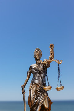 Back side view of Themis - Lady of Justice on blue sky background