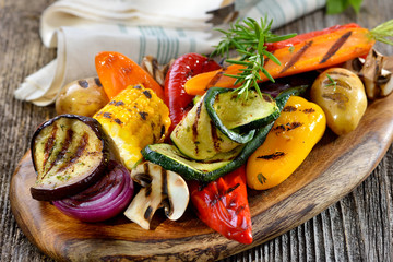 Kleurrijke, gemengde groenten van de grill met feta en olijfolie, met vers witbrood - Gemengde Griekse groenten met fetakaas op een houten snijplank geserveerd met brood
