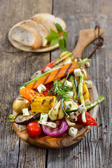 Buntes, gemischtes Gemüse vom Grill mit Feta und Olivenöl, dazu frisches Weißbrot - Mixed Greek  vegetables with feta cheese on a wooden cutting board served with bread